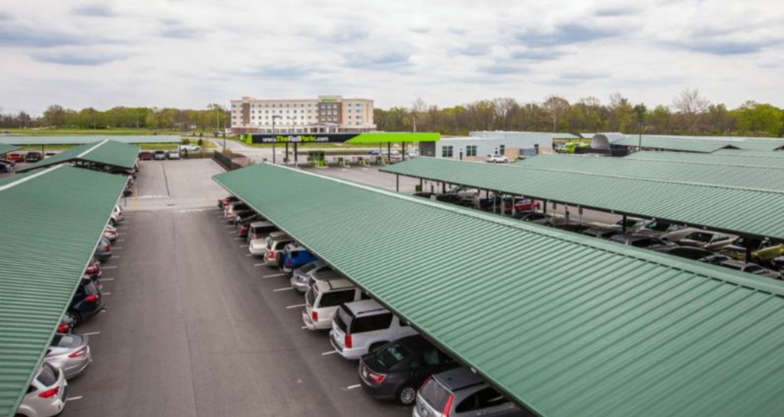 Covered parking lot with cars and a hotel.