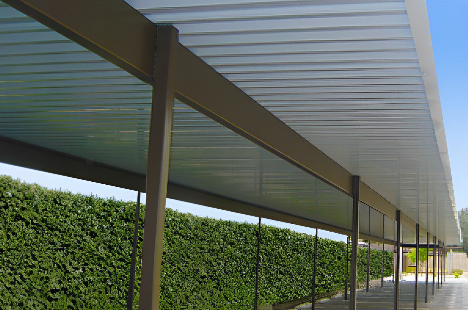 Covered walkway with green hedge.