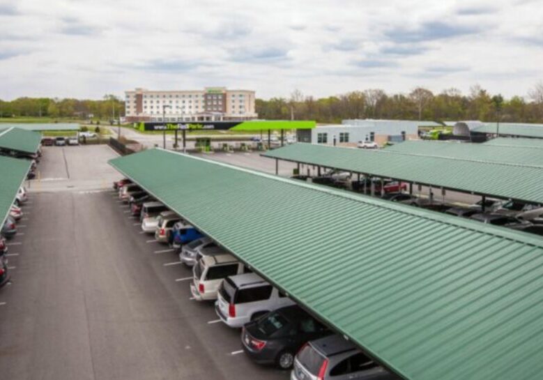 Covered parking lot with cars and a hotel.